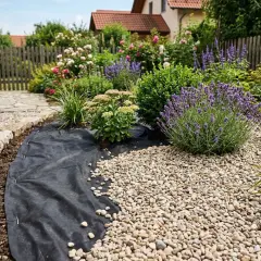 Gartenarbeit: Unkrautvlies verlegen, um Beete mit Kies zu bedecken und Pflanzen wie Lavendel zu schützen. Handschuhe und Spaten liegen bereit.