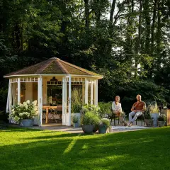 Ein Paar genießt die Abendsonne im Garten. Der Pavillon und die Bäume schaffen angenehme Schatten im Garten.
