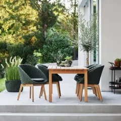 Moderne Terrassengestaltung mit Teakholztisch, grünen Korbsesseln und Pflanzen. Tolle Terrassen Ideen für Ihr Zuhause.