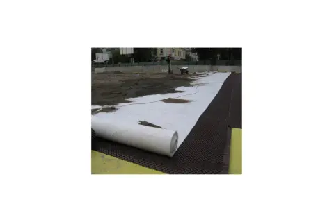Vlies unter Pflaster wird ausgerollt. Bauarbeiter bereiten den Untergrund für eine neue Fläche vor.