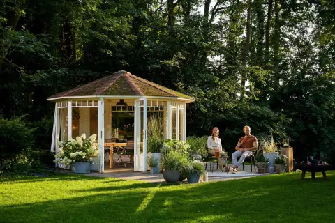 Ein Paar genießt die Abendsonne im Garten. Der Pavillon und die Bäume schaffen angenehme Schatten im Garten.