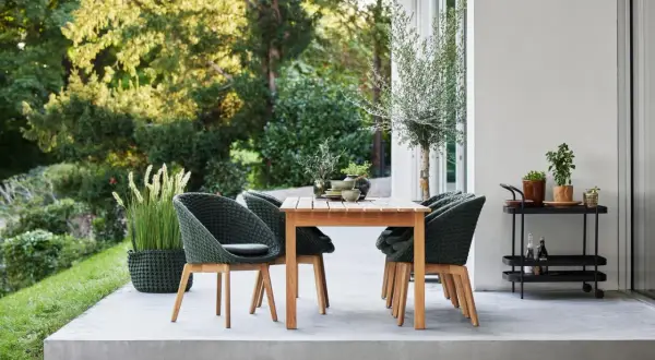 Moderne Terrassengestaltung mit Teakholztisch, grünen Korbsesseln und Pflanzen. Tolle Terrassen Ideen für Ihr Zuhause.