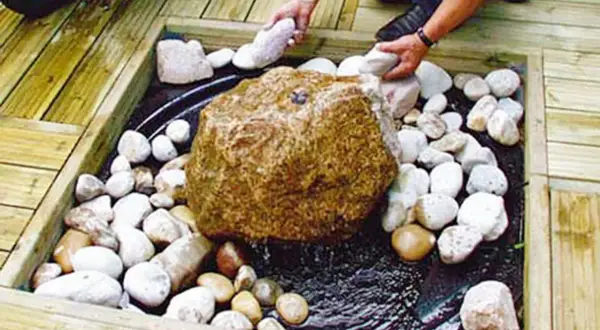 Ein Quellstein im Garten: Ideen für ein beruhigendes Wasserspiel mit Natursteinen und Holzdeck.
