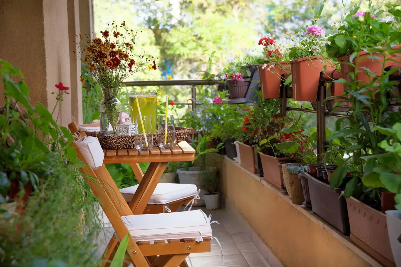 Gem&uuml;tliche Balkon-Oase mit Holztisch, St&uuml;hlen und vielen Pflanzen. Coole Gartenideen einfach umgesetzt f&uuml;r entspannte Stunden im Gr&uuml;nen.