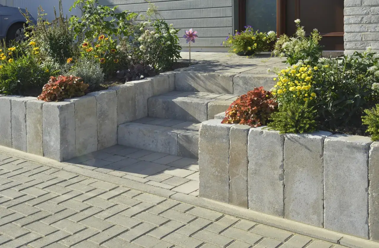 Schöne Steintreppen mit blühenden Beeten. Die Palisaden setzen den Gartenbereich elegant ab.