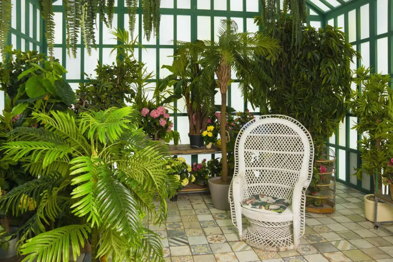 Ein &uuml;ppiger Wintergarten mit vielen Pflanzen und einer wei&szlig;en Korbstuhl-Oase. Tolle anbau wintergarten ideen f&uuml;r Ihr gr&uuml;nes Paradies.