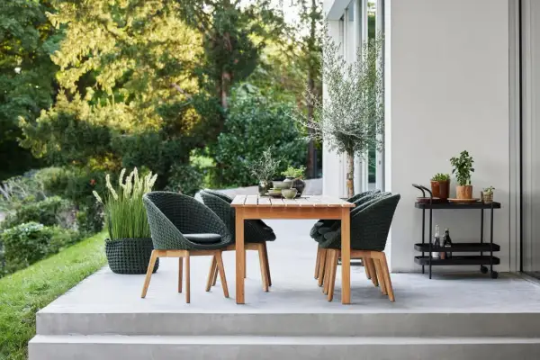 Moderne Terrassengestaltung mit Teakholztisch, grünen Korbsesseln und Pflanzen. Tolle Terrassen Ideen für Ihr Zuhause.